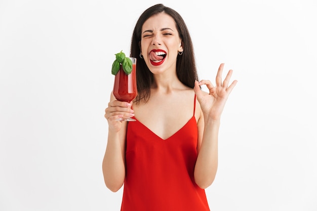 Foto de joven mujer emocionada feliz posando aislado beber cóctel mostrando gesto bien.