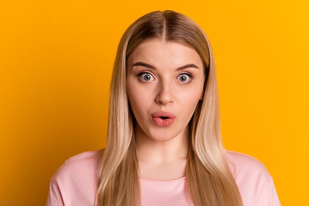 Foto de una joven mujer impresionada con información inesperada frente a una reacción aislada sobre un fondo de color amarillo