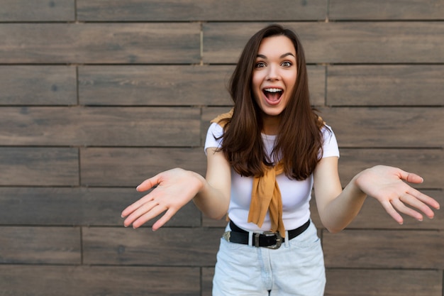 Foto de joven mujer morena atractiva encantadora feliz emocional con ropa elegante de pie