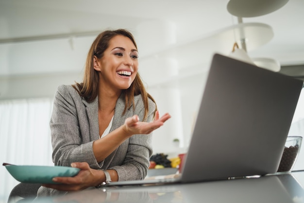 Una foto de una joven mujer de negocios usando su laptop mientras desayunaba en casa.