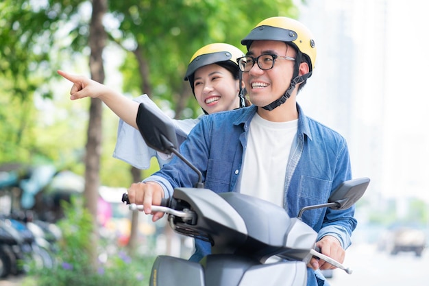 Foto de una joven pareja asiática conduciendo una moto