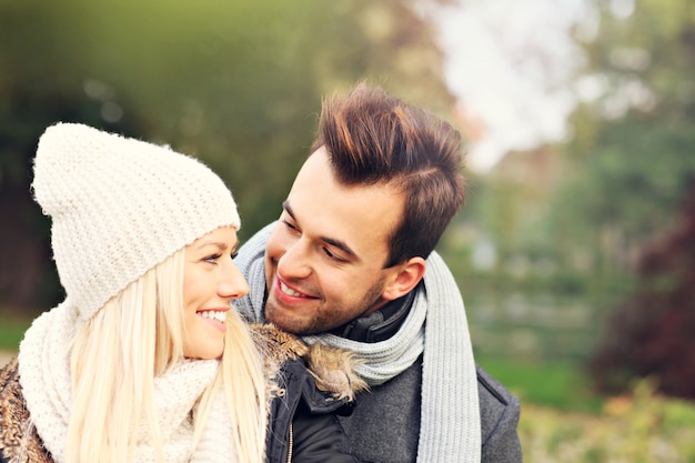Una foto de una joven pareja romántica abrazándose en el parque en otoño