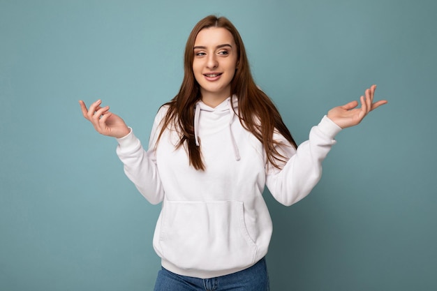 Foto de joven positiva feliz hermosa mujer morena con emociones sinceras vistiendo sudadera con capucha blanca