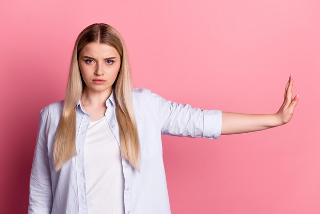 Foto de una joven que muestra la mano suficiente para bloquear el rechazo disgustado aislado sobre un fondo de color rosa