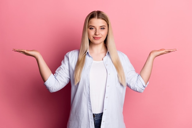 Foto de una joven que se toma de la mano una propuesta promocional de un producto anunciada aislada sobre un fondo de color rosa