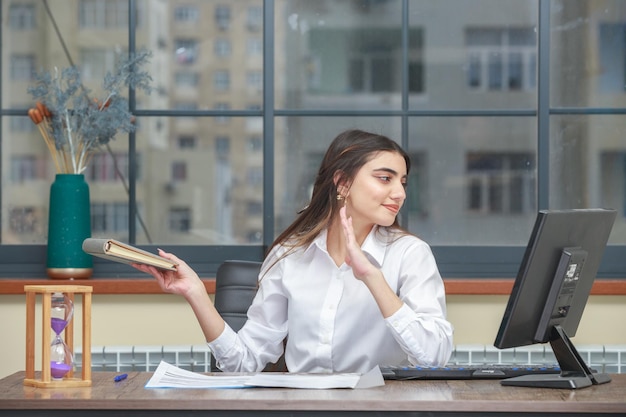 Foto de una joven sentada en el escritorio y sosteniendo su cuaderno