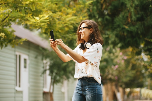 Foto de una joven sonriente tomando una foto selfie afuera