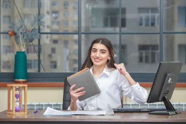 Foto de una joven sosteniendo un cuaderno y apretando su puño