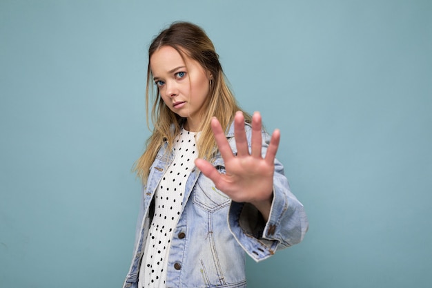 Foto de joven triste molesta hermosa mujer rubia con emociones sinceras vistiendo chaqueta azul jean