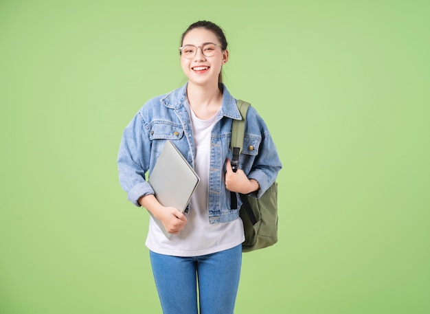 Foto de joven universitaria asiática sobre fondo verde