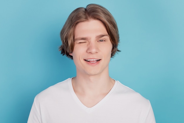 Foto de joven wink eye use camiseta blanca aislado sobre fondo azul.