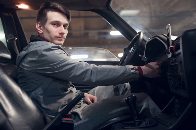 Foto del lado del hombre mirando a la cámara sentado en el coche