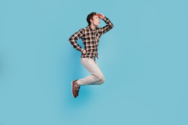 Foto lateral de perfil de corpo inteiro de um jovem olhando para a frente venda salto isolado sobre fundo de cor azul