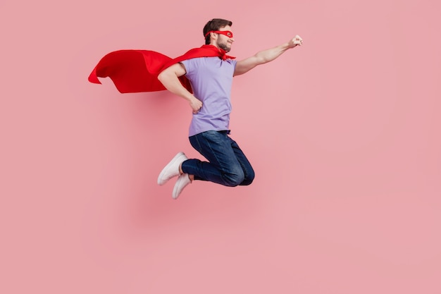 Foto lateral de perfil em tamanho real do jovem super-homem forte poder de segurança pula pronto para ajudar isolado sobre fundo de cor rosa