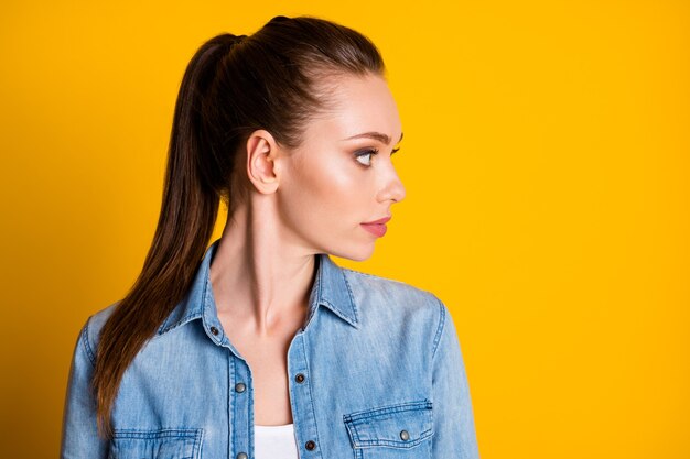 La foto lateral de perfil de una chica bastante encantadora tiene terapia de tratamiento de cuidado del cabello demuestra que la cola de caballo usa ropa de buen aspecto aislada sobre fondo de colores vivos