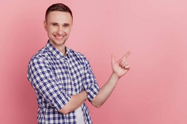 Foto lateral de perfil de chico joven que señala la decisión de elección de anuncio de espacio vacío de índice aislado sobre fondo rosa