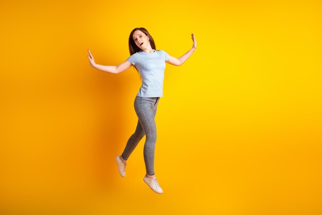 Foto lateral de perfil de tamaño completo de una joven bonita que camina salta la elegancia aislada sobre el fondo de color amarillo