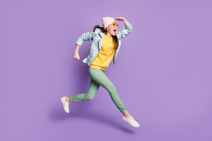 Foto foto lateral de perfil de tamaño completo de niña alegre emocionada ver descubrir increíble descuento saltar correr desgaste rápido sombreros pantalones verdes pantalones chaqueta de cuero aislado fondo de color púrpura