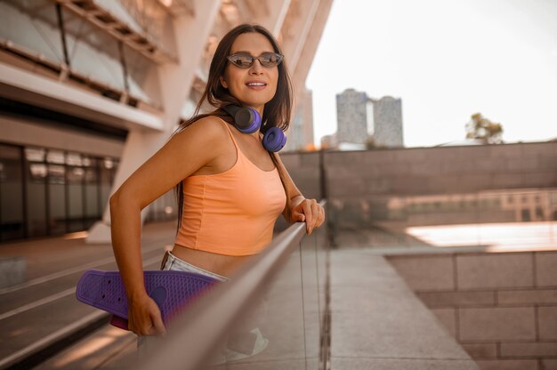 Una foto de una linda chica en top naranja en el fondo urbano