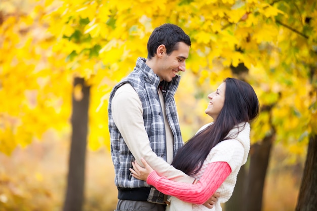 Foto de linda pareja abrazándose en el maravilloso fondo de árboles amarillos