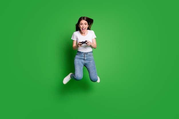 Foto de longitud completa del videojuego de salto de niña loca aislado sobre fondo de color verde brillante