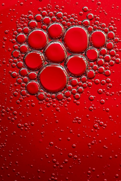 Foto macro. Bolhas de óleo na superfície da água. Fundo vermelho. Cor vermelha em água e óleo.