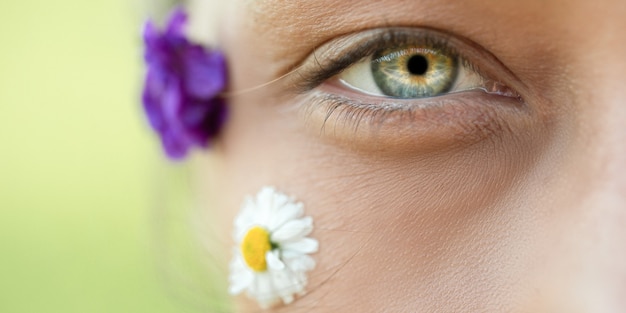 Foto macro do belo olho de uma mulher e flores silvestres no rosto