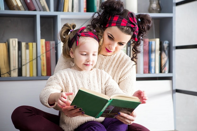 Foto de madre e hija sentadas en el suelo y leyendo