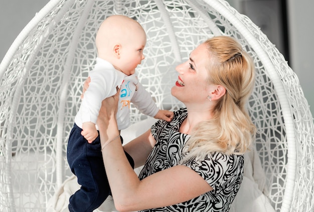 Foto de madre e hijo sentados en una silla redonda de moda