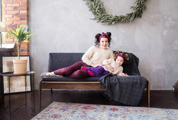 Foto de mamá e hija juntas en casa en el sofá