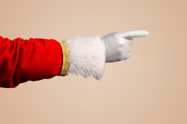 Foto de la mano enguantada de Santa Claus en gesto señalador Santa Claus apuntando con sus dedos sobre pastel