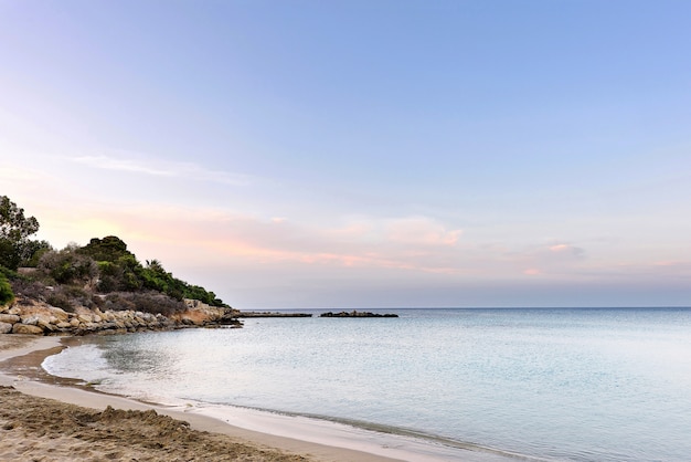 Foto del mar en protaras, isla de Chipre, con rocas y arena al atardecer