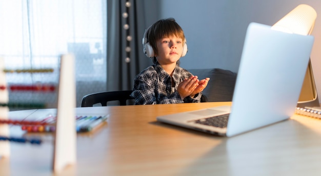 Foto média de menino fazendo cursos virtuais no laptop