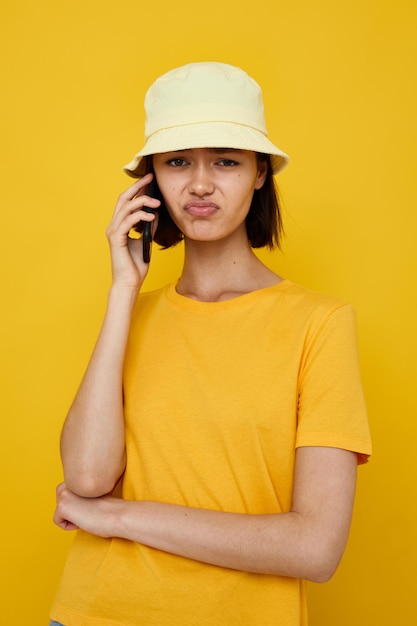 foto menina bonita t-shirt amarela e estilo de verão chapéu com telefone Estilo de vida inalterado. Foto de alta qualidade