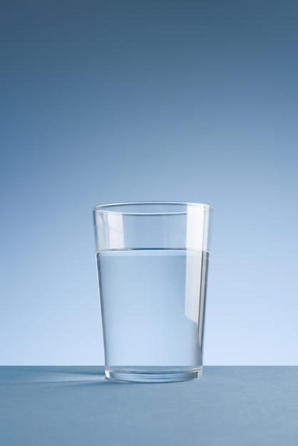 Foto minimalista de um copo de água potável limpa em fundo azul