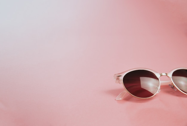 Foto minimalista de un par de gafas de sol sobre un fondo rosa pastel, conceptos de diseño y verano