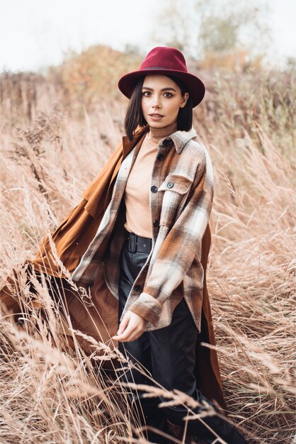 Foto de moda de joven bella dama en paisaje otoñal con flores secas