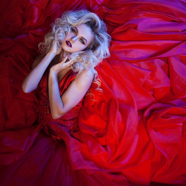 Foto de moda de mujer joven magnífica en vestido rojo. Retrato de estudio