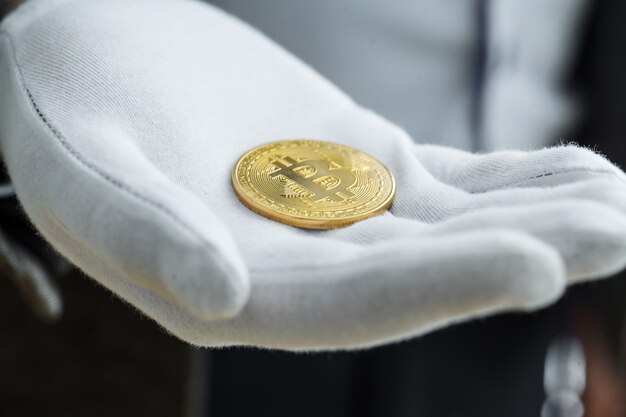 Foto de monedas virtuales bitcoin doradas en una mano