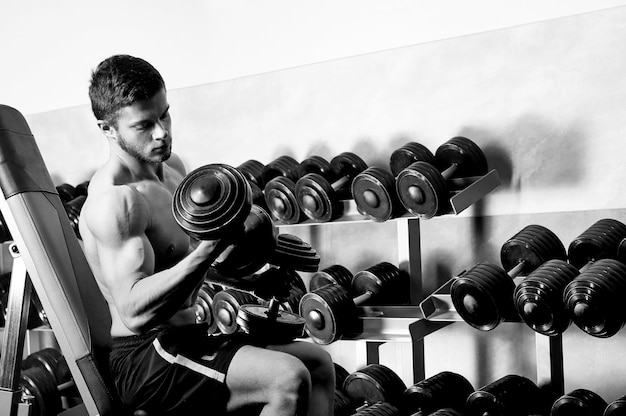 Foto monocroma de un hombre sin camisa rasgado haciendo ejercicio