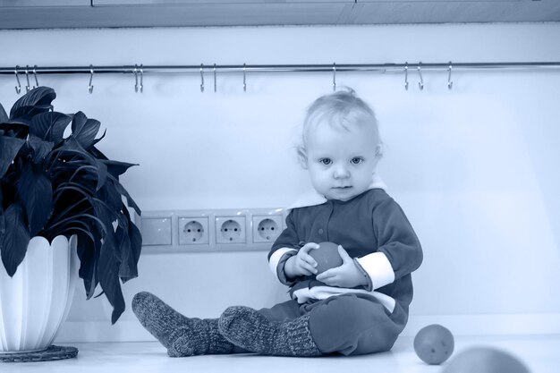 Foto monocroma de niño rubio en la cocina se sienta en una mesa