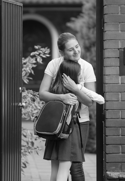 Foto monocromática de mãe e filha felizes se encontrando depois da escola