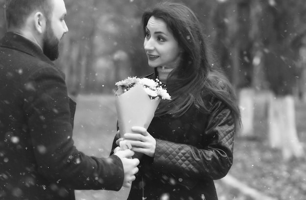 Foto monocromática de um encontro em um parque de amantes em um banco na neve