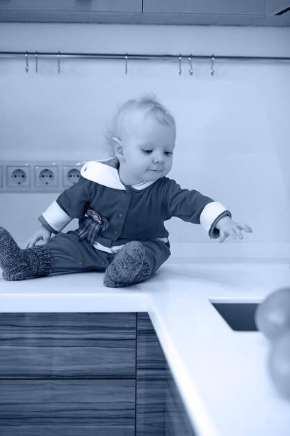 Foto monocromática de uma criança loira na cozinha sentada em uma mesa