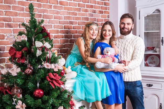 Foto mostrando felicidade jovem família, comemorando o natal em casa, olhando para a câmera e posando para uma foto de família. interior, foto de estúdio