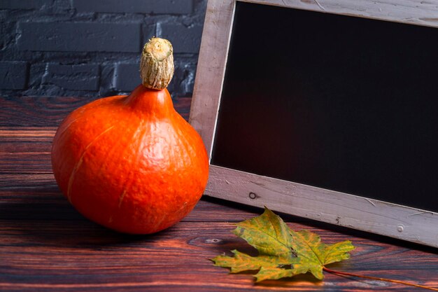 Foto la foto muestra una calabaza de hokkaido naranja con una hoja y una pizarra con pared negra