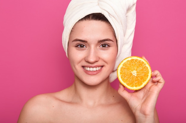 Foto de mujer adorable con la mitad de naranja en la mano