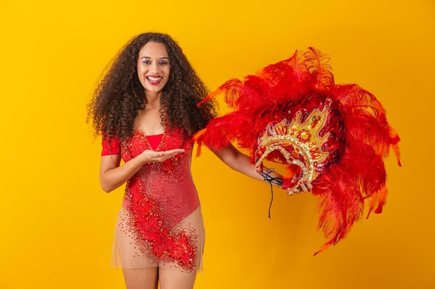 Foto de mujer afro vestida para el carnaval con traje de bailarina sosteniendo su corona en la mano.