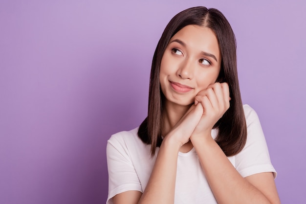 Foto de mujer atractiva joven feliz sonrisa positiva manos toque la mejilla sueño mirar espacio vacío aislado sobre fondo de color púrpura