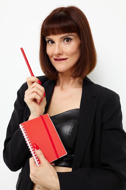 Foto mujer bonita libreta roja y lápiz posando fondo claro